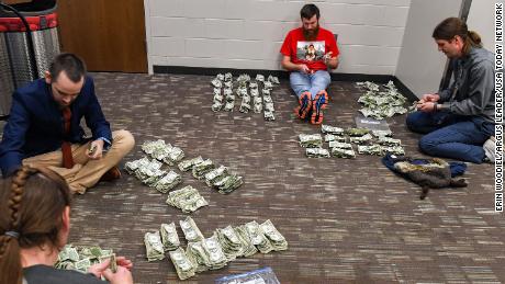 Teachers count the dollar bills they collected at the Sioux Falls Stampede game.