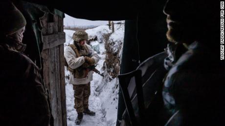 Ukrainian soldiers in a frontline trench position in Donbas shelter from the extreme cold.