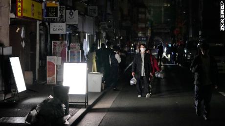 People walk on the street during a power outage in Tokyo.