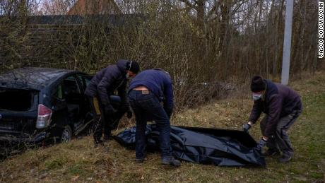 Volunteers collect the body of a man shot dead in his car in Borodianka. They say he was transporting medical supplies.