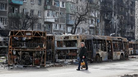 A local resident walks through a street past burned-out buses in Mariupol on April 19, 2022.