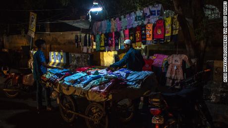 A vendor sells fabrics under emergency lighting connected to a motorcycle during a power outage in Karachi, Pakistan on June 8.