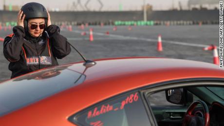 Afnan Almarglani, the first Saudi woman to be certified as an autocross instructor, adjusts her helmet in front of her car at the Derab circuit in the Saudi Arabian capital Riyadh on June 26. 