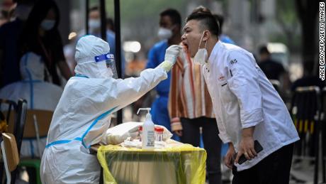 A health worker takes a swab from a man at a makeshift testing site outside a shopping mall in Beijing on June 15, 2022.