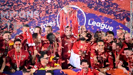 Jordan Henderson lifts the Premier League trophy alongside Mohamed Salah as they celebrate winning the league.