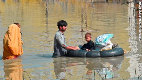 A family wades through a flood-stricken area after heavy monsoon rains in Khyber Pakhtunkhwa's Charsadda district on August 29, 2022.