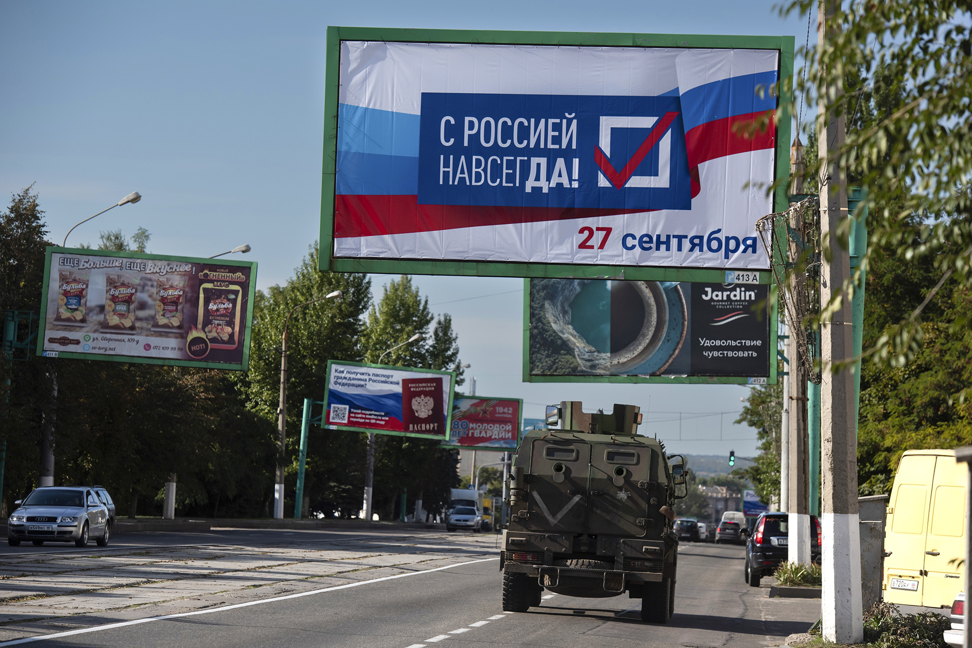 A military vehicle drives down a street with a billboard reading "With Russia Forever, September 27th" ahead of a referendum in Luhansk, eastern Ukraine, on September 22.